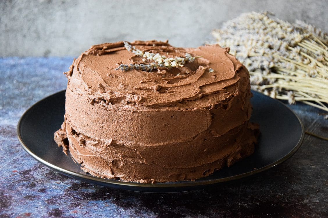 A chocolate cake with buttercream icing, decorated with a sprig of lavender